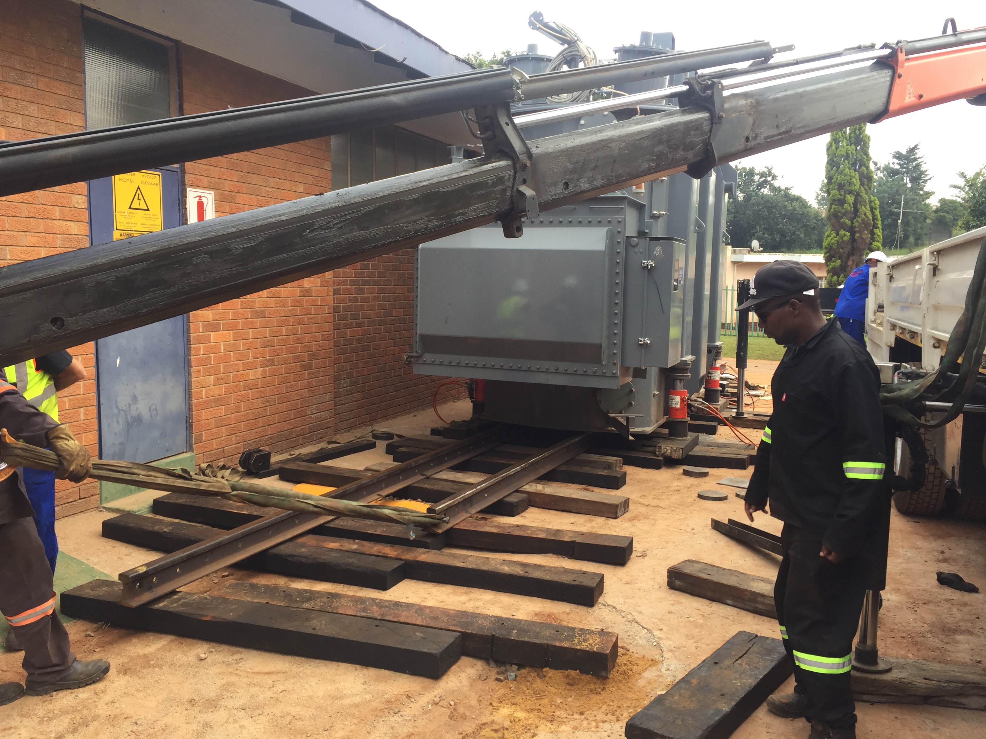 Jack-and-slide rigging operation moving a transformer on timber rails
