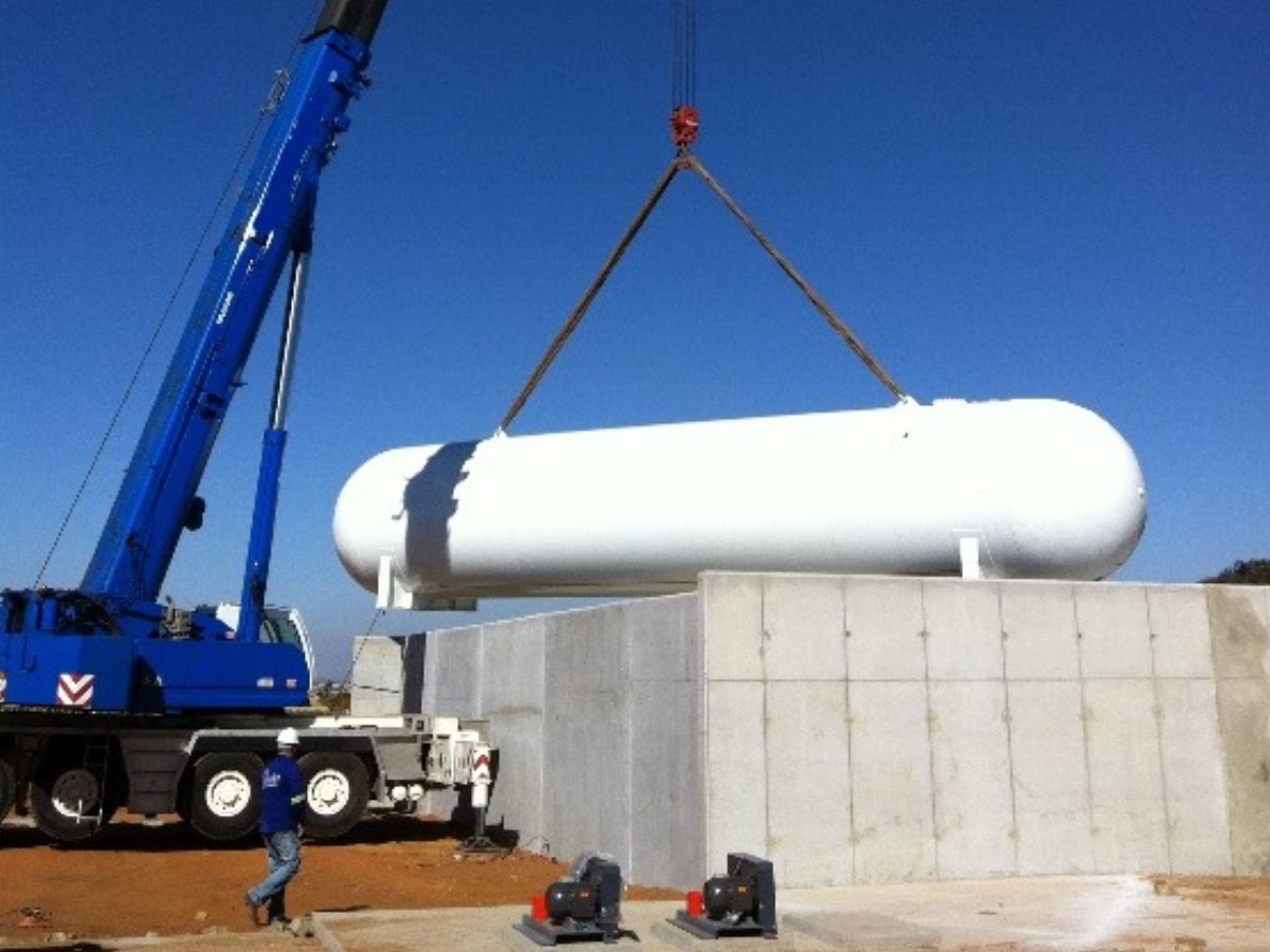 Blue Liebherr mobile crane placing a white LPG pressure vessel