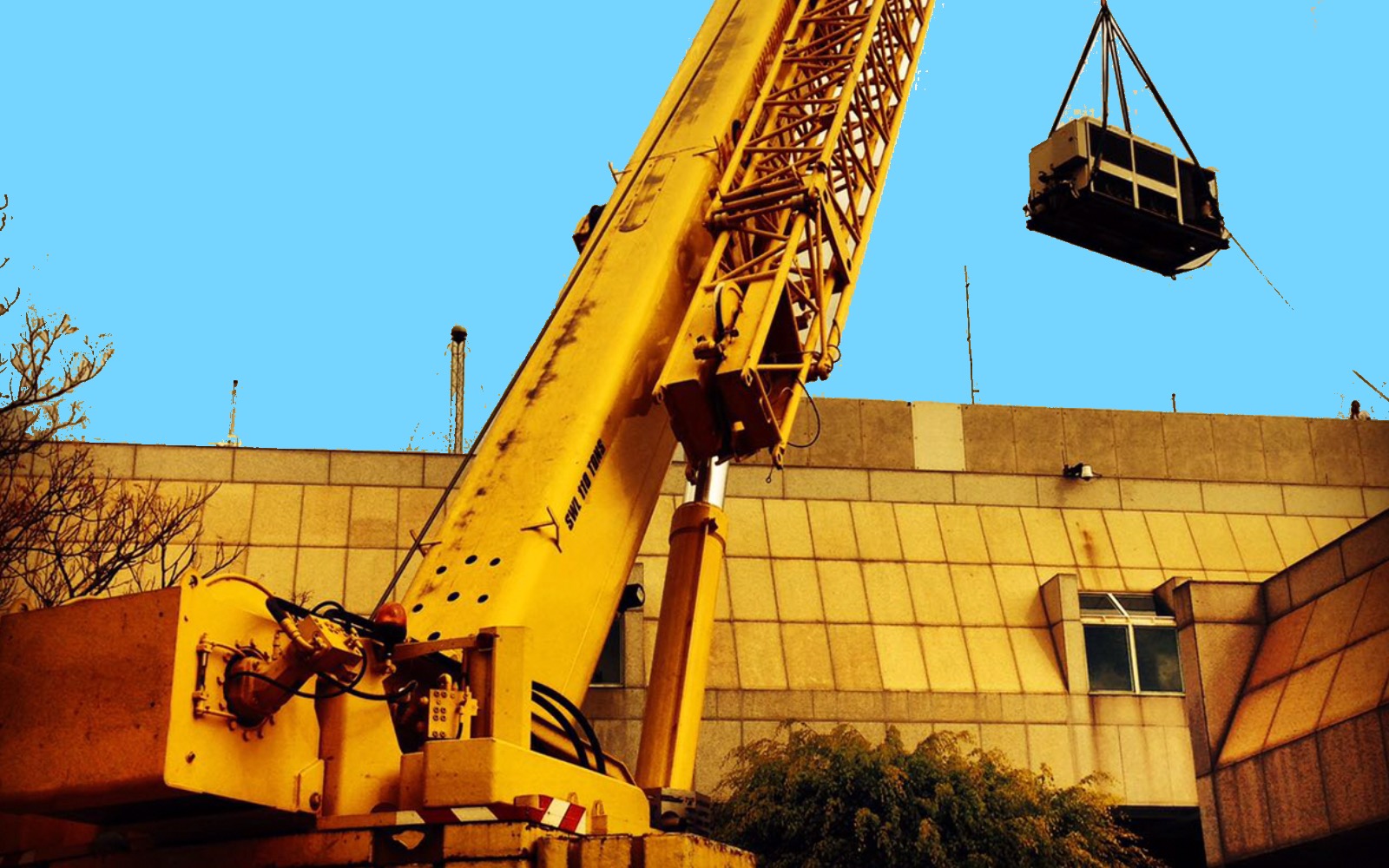 50-ton mobile crane lifting an aircon unit — typical medium-band industrial lift