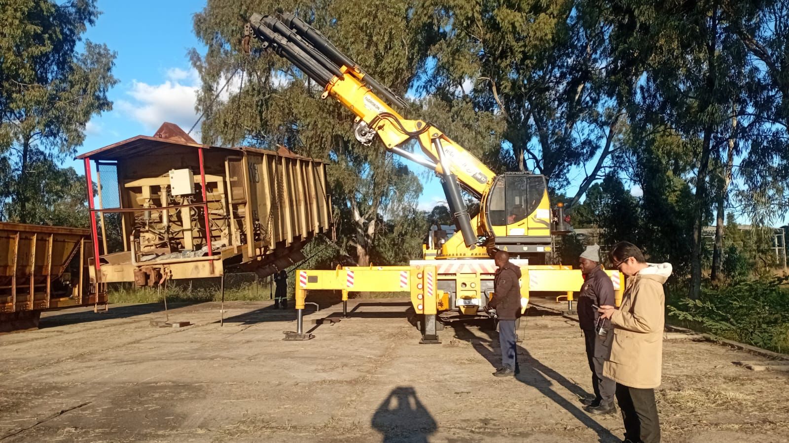 Remote-controlled crane truck working alongside a rigging team